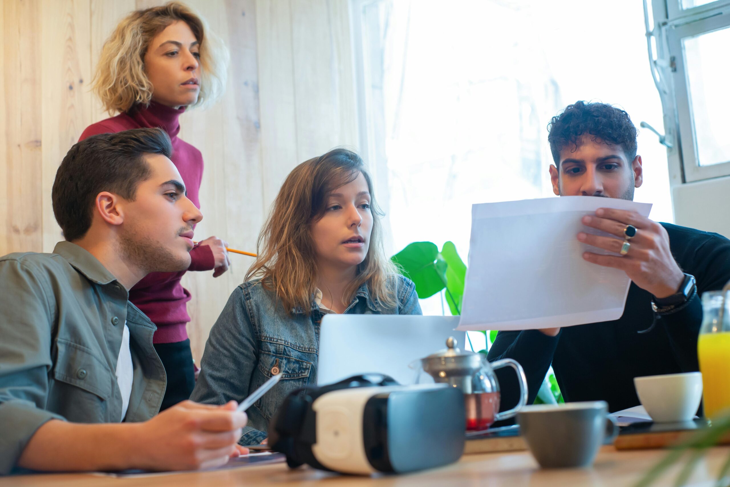 Four colleagues engaged in a productive discussion in a well-lit office environment, showcasing teamwork and diversity.